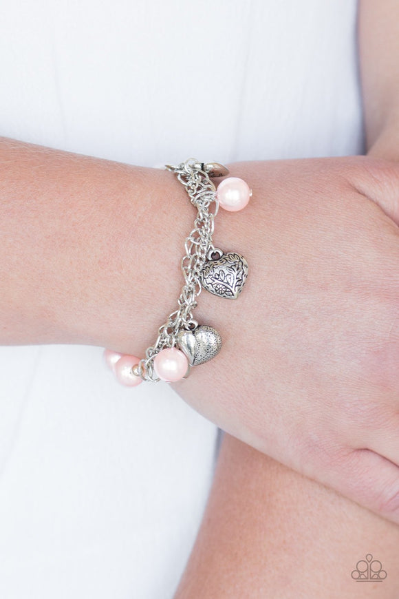 More Amour - Pink - Paparazzi Accessories - Attached to a section of shimmery silver chain, pearly pink and dainty silver beads are threaded along a stretchy band. Mismatched silver heart charms swing from the glistening chain, creating a flirty fringe.   Sold as one individual bracelet.