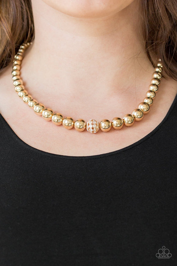 High-Stakes FAME - Gold - Paparazzi Accessories -  Gradually increasing in size near the center, glistening gold beads are threaded along an invisible wire below the collar. Encrusted in glassy white rhinestones, a sparkling gold bead adorns the center for a refined finish. Features an adjustable clasp closure.  Sold as one individual necklace. Includes one pair of matching earrings.  Paparazzi Accessories jewelry is always lead free and nickel free.