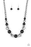 Hollywood HAUTE Spot - Black - Paparazzi Accessories -  A collection of oversized shiny black, silver rings, and asymmetrical silver beads are threaded along an invisible wire below the collar. White rhinestone encrusted rings are sprinkled between the refined beading for a statement-making finish. Features an adjustable clasp closure.  Sold as one individual necklace with matching earrings.