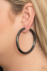 Curve Ball - Black - Paparazzi Accessories -  Item #P5HO-BKXX-185XX A thick gunmetal bar delicately curls into a glistening oversized hoop for a retro look. Earring attaches to a standard post fitting. Hoop measures approximately 2 1/4" in diameter.  Sold as one pair of hoop earrings.