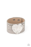 Flauntable Flirt - Silver - Paparazzi Accessories -   Item #P9DI-URSV-133XX Encrusted in blinding white rhinestones, an oversized silver heart frame is studded in place across the front of a gray leather band, creating a flirtatious centerpiece around the wrist. Features an adjustable snap closure.  Sold as one individual bracelet.