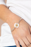 Cottage Season - White - Paparazzi Accessories -  Item #P9WH-WTXX-216XX Encased in a glassy fitting, a whimsical white daisy centerpiece attaches to two arcing silver bars around the wrist for an enchanting floral look. Features an adjustable clasp closure.  Sold as one individual bracelet.