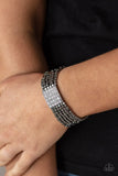 Star-Studded Showcase - Black - Paparazzi Accessories -  Item #P9BA-BKXX-077XX Held in place by a square centerpiece encrusted in row after row of dazzling white rhinestones, a dainty collection of gunmetal cube beads are threaded along stretchy bands around the wrist, creating shimmery layers.  Sold as one individual bracelet.