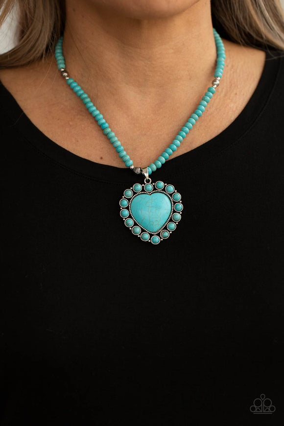 A Heart Of Stone - Blue - Paparazzi Accessories -   Item #P2SE-BLXX-436XX Bordered by dainty turquoise stones, an oversized turquoise stone heart pendant swings from the bottom of a turquoise stone and silver beaded display below the collar for a flirtatiously earthy fashion. Features an adjustable clasp closure.  Sold as one individual necklace. Includes one pair of matching earrings.  2021 LIFE OF THE PARTY (LOP) APRIL