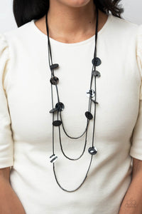 Alluring Luxe - Black - Paparazzi Accessories -  Item #P2SE-BKXX-289XX Shining wavy gunmetal discs and black leather discs adorn a trio of lengthened subtly shimmering black cords. Rows of dainty gunmetal cylinders are threaded along the bottom of each cord adding luxurious allure to the piece. Features an adjustable clasp closure.  Sold as one individual necklace. Includes one pair of matching earrings.