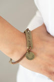 Believe and Let Go - Brass - Paparazzi Accessories -  Item #P9WD-URBR-040XX An antiqued disc stamped in the word, "believe" and a brass plate stamped in the phrase, "and let go," are knotted in place around the wrist with layers of brown suede cording, creating a motivational centerpiece. Features an adjustable clasp closure.  Sold as one individual bracelet.