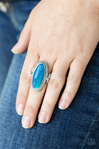 Oval Oasis - Blue - Paparazzi Accessories -  Item #P4ST-BLXX-005XX Featuring a glassy iridescence, an oval Blue Tint acrylic bead is pressed into the center of textured silver fittings, creating a mystical centerpiece atop the finger. Features a dainty stretchy band for a flexible fit.  Sold as one individual ring.