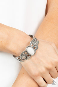 Solar Solstice - White - Paparazzi Accessories -  Item #P9SE-WTXX-227XX An oval white stone is pressed into the center of a studded silver frame atop an airy silver cuff embellished in studded sun-like frames for an earthy pop of seasonal color around the wrist.  Sold as one individual bracelet.