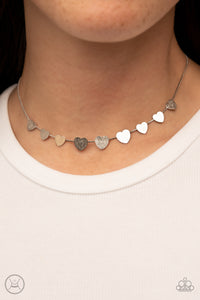 Dainty Desire - Silver - Paparazzi Accessories -  Item #P2CH-SVXX-078XX Delicately scratched in shimmer, a dainty collection of flat silver heart frames gradually increases in size along a shiny silver snake chain around the neck for a flirtatious fashion. Features an adjustable clasp closure.  Sold as one individual choker necklace. Includes one pair of matching earrings.