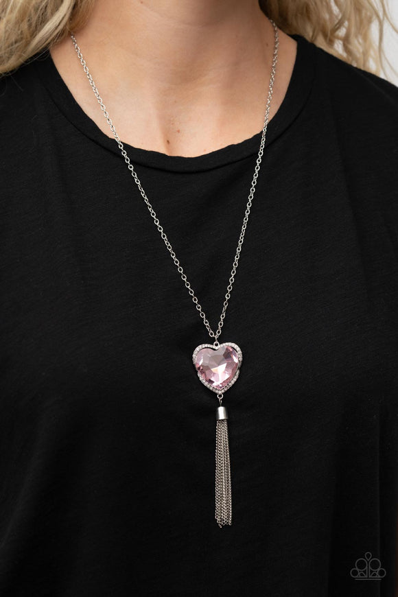 Finding My Forever - Pink - Paparazzi Accessories -  Item #P2WH-PKXX-418XX Bordered in a ribbon of glassy white rhinestones, an oversized pink heart-shaped gem seemingly floats at the bottom of an extended silver chain. A shimmery silver chain tassel dances from the bottom of the sparkly pendant for a flirtatious finish. Features an adjustable clasp closure.  Sold as one individual necklace. Includes one pair of matching earrings.