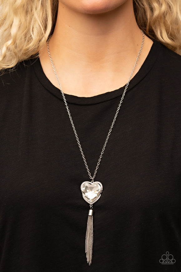 Finding My Forever - White - Paparazzi Accessories -  Item #P2WH-WTXX-295XX Bordered in a ribbon of glassy white rhinestones, an oversized white heart-shaped gem seemingly floats at the bottom of an extended silver chain. A shimmery silver chain tassel dances from the bottom of the sparkly pendant for a flirtatious finish. Features an adjustable clasp closure.  Sold as one individual necklace. Includes one pair of matching earrings.