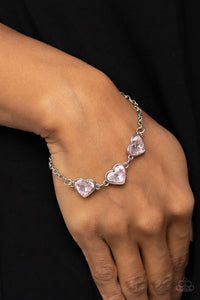 Item #P9WH-PKXX-297XX Nestled in silver frames, a trio of glittery pink heart-shaped gems delicately links across the wrist for a dash of swoon-worthy shimmer. Features an adjustable clasp closure.  Sold as one individual bracelet.