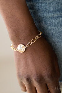 All Aglitter - Gold - Paparazzi Accessories  A dramatic golden gem attaches to a shiny gold chain, creating a blinding centerpiece atop the wrist. Features a toggle closure.  Sold as one individual bracelet.   Get The Complete Look! Necklace: "She Sparkles On - Gold" (Sold Separately) SN0198