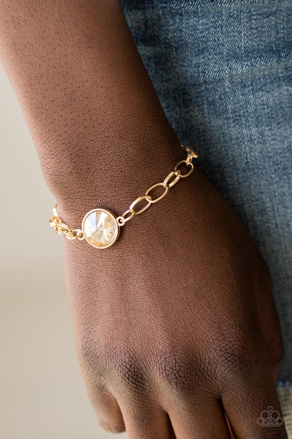 All Aglitter - Gold - Paparazzi Accessories  A dramatic golden gem attaches to a shiny gold chain, creating a blinding centerpiece atop the wrist. Features a toggle closure.  Sold as one individual bracelet.   Get The Complete Look! Necklace: 