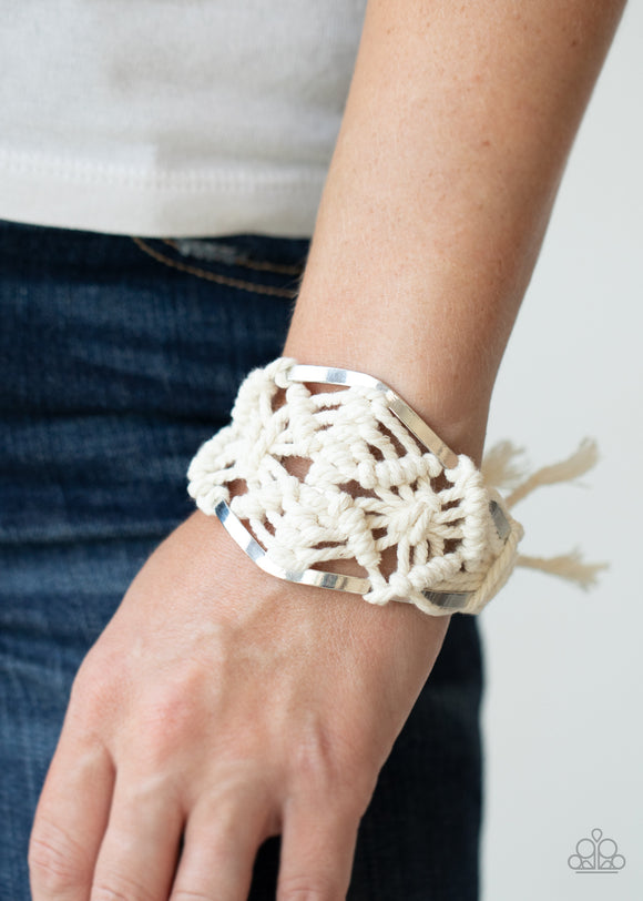 Macrame Mode - White White cording decoratively knots and weaves around an airy silver cuff for a macramé inspired look. Knotted around the ends, white tassels flair out from bottoms of the cuff for a wanderlust finish.  Sold as one individual.