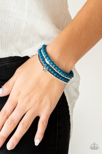 Blooming Buttercups - Blue - Paparazzi Accessories - Mismatched silver beads and strands of glassy blue beads are threaded along stretchy bands. Infused with silver accents, dainty rose blossoms adorn the wrist for a seasonal finish.  Sold as one set of four bracelets.