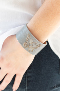 Flirty Flutter - Silver - Paparazzi Accessories - Stamped in a whimsical butterfly, a rustic piece of gray leather wraps around the wrist for a seasonal flair. Features an adjustable snap closure.  Sold as one individual bracelet.