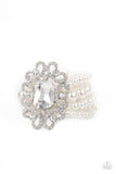 Rule The Room - White - Paparazzi Accessories -  Item #P9RE-WTXX-415XX A dramatically oversized emerald cut gem adorns the center of a white rhinestone encrusted filigree filled frame. The blinding centerpiece attaches to bubbly rows of pearl beaded stretchy bracelets, creating a gorgeous statement piece.  Sold as one individual bracelet.