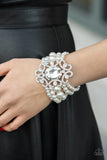 Rule The Room - White - Paparazzi Accessories -  Item #P9RE-WTXX-415XX A dramatically oversized emerald cut gem adorns the center of a white rhinestone encrusted filigree filled frame. The blinding centerpiece attaches to bubbly rows of pearl beaded stretchy bracelets, creating a gorgeous statement piece.  Sold as one individual bracelet.