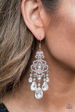 Queen Of All Things Sparkly - White - Paparazzi Accessories -  Item #P5RE-WTXX-485XX Gradually increasing in size, glassy white teardrop gems create a dramatic fringe at the bottom of a decorative silver frame swirling with dainty white rhinestones for a timelessly over-the-top sparkle. Earring attaches to a standard fishhook fitting.  Sold as one pair of earrings.