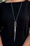 Times Square Stunner - Silver - Paparazzi Accessories  Encrusted in smoky hematite rhinestones, two squared, silver frames link at the bottom of a lengthened silver box chain. Flattened silver chains stream from the bottom of the stacked pendant, creating an edgy tassel. Features an adjustable clasp closure.  Sold as one individual necklace. Includes one pair of matching earrings.