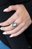 PAPARAZZI ACCESSORIES - Glass Half-COLORFUL - White An opalescent white gem is pressed into a scalloped silver frame radiating with shiny silver studs, creating a whimsical frame atop the finger. Features a dainty stretchy band for a flexible fit.  Sold as one individual ring.