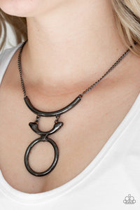 Walk Like An Egyptian - Black - Paparazzi Accessories -   Two glistening gunmetal crescents attach to a large gunmetal hoop, creating a tribal inspired pendant below the collar. Features an adjustable clasp closure.  Sold as one individual necklace. Includes one pair of matching earrings.