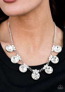 GLOW-Getter Glamour - White - Paparazzi Accessories  Crowned in a trio of dainty white rhinestones, an exaggerated display of oversized white gems delicately links below the collar for a glamorous glow. Features an adjustable clasp closure.  Sold as one individual necklace. Includes one pair of matching earrings.