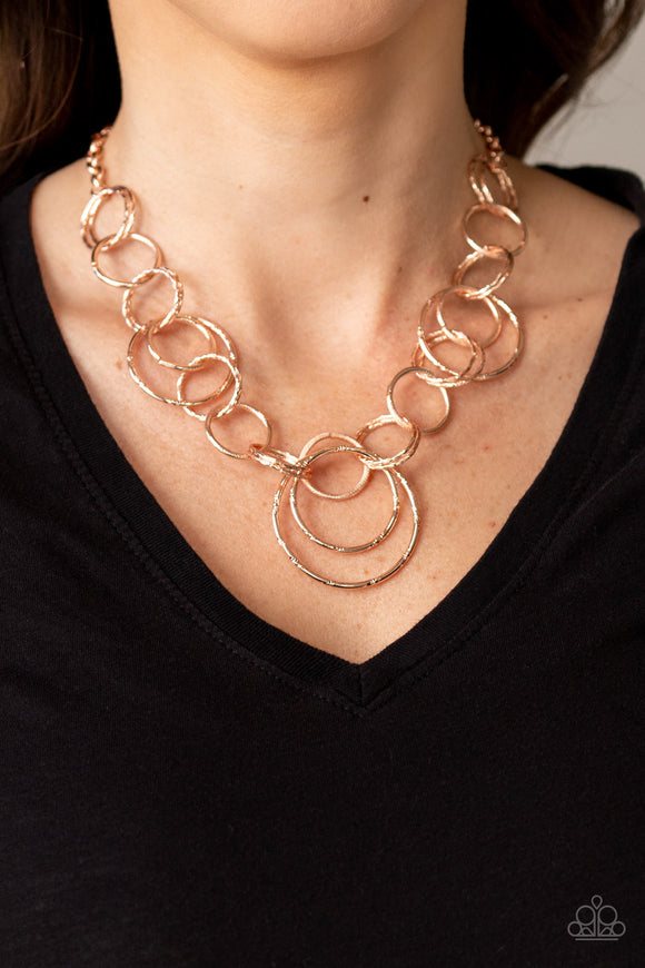 Ringing Relic - Rose Gold - Paparazzi Accessories -  Item #P2BA-GDRS-042XX Varying in size and texture, a collision of shimmery rose gold rings link below the collar for a dizzying look. Features an adjustable clasp closure.  Sold as one individual necklace. Includes one pair of matching earrings.