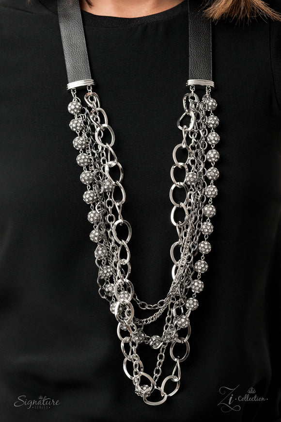 The Arlingto - 2020 Zi Signature - Paparazzi Accessories  Attached to two strips of black leather, strands of bedazzled white rhinestone encrusted silver beads drape between an exaggerated display of mismatched silver and gunmetal chains down the chest. With its edgy sparkle, grunge meets glamour in this heart-stopping statement-maker. Features an adjustable clasp closure.  Named after 2020 Rock the Runway winner, Jose Arlingto L.  Sold as one individual necklace. Includes one pair of matching earrings.