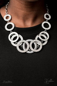 The Keila - 2020 Zi Signature - Varying in size and shimmer, shiny silver rings and white rhinestone encrusted hoops sporadically link into two bubbly rows below the collar. The flawless frames increase in size at the center for double the jaw-dropping dazzle. Features an adjustable clasp closure.  Named after 2020 Rock the Runway winner, Keila R.  Sold as one individual necklace. Includes one pair of matching earrings.