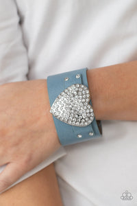 Flauntable Flirt - Blue - Paparazzi Accessories -   Encrusted in blinding white rhinestones, an oversized silver heart frame is studded in place across the front of a blue leather band, creating a flirtatious centerpiece around the wrist. Features an adjustable snap closure.  Sold as one individual bracelet.